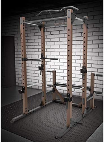 The Steelbody Monster Cage installed in a home gym setting against a white brick wall, sitting on a black rubber tile floor, in a finished room rather than a studio shot